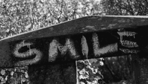 Black and white image. Smile written in chalk on a board