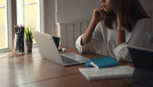 Person sat at laptop surrounded by books and paper