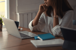 Person sitting at a laptop surrounded by books and paper