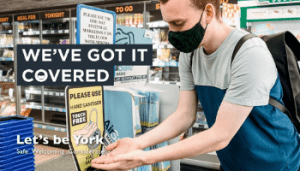 Person wearing a face covering and hand sanitising their hands