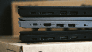 Side view of 3 closed laptops piled on top of each other on top of a box