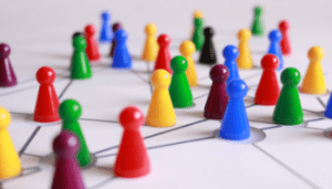 IMAGE: Brightly coloured plactic pawns set on a piece of paper connected by lines to represent an interconnected network.