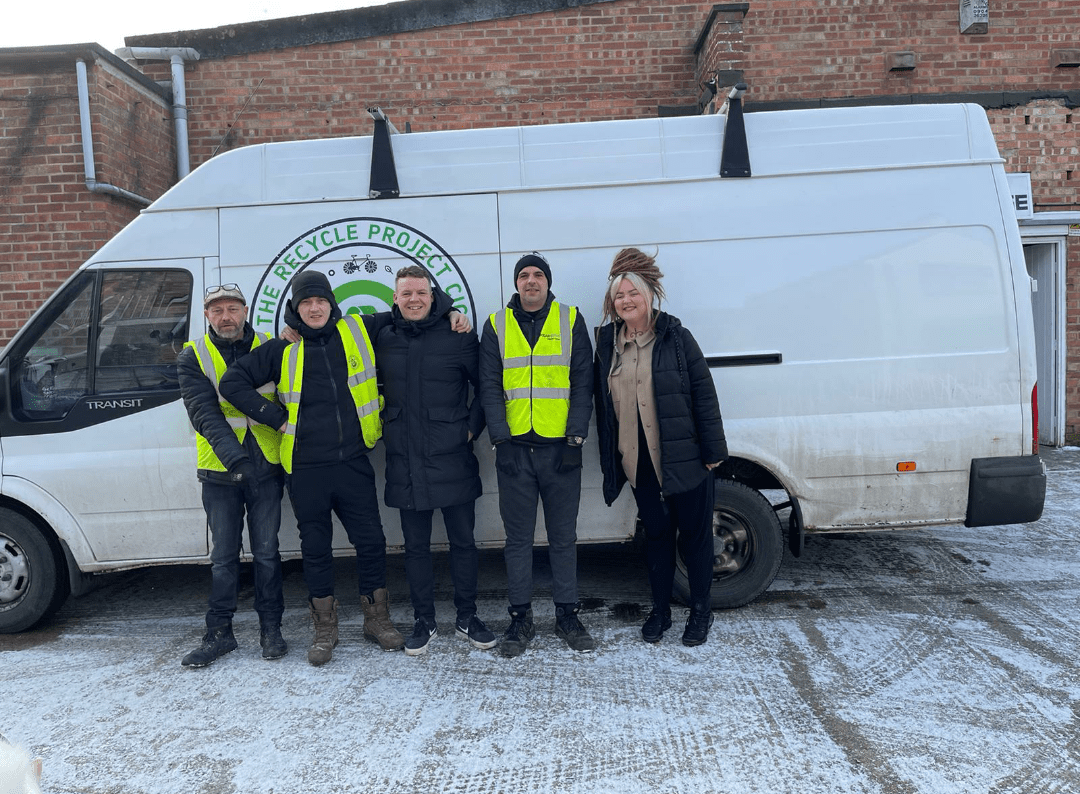 Recycling Project members and van Five members of The Recycling Project wearing Hivis jackets in front of their van.
