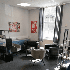 In the corner next to a large window there are 4 comfortable chairs with a coffee table in the middle