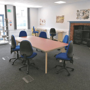 Large meeting table in the centre of the room with 6 chairs set around it