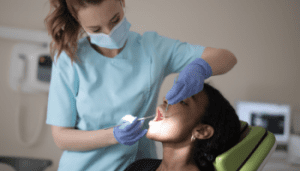 Image of a female dentist with gloves on checking a female patients teeth