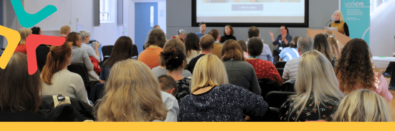 Supporting VCSE Organisations in York Image of a large group of people sat down listening to a speaker at the front,