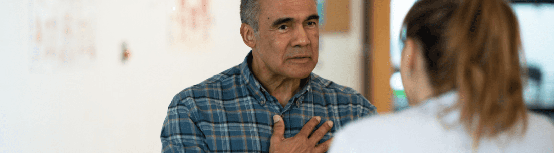 Social Prescribers A gentleman has his hand on his chest whilst having a conversation with a woman.