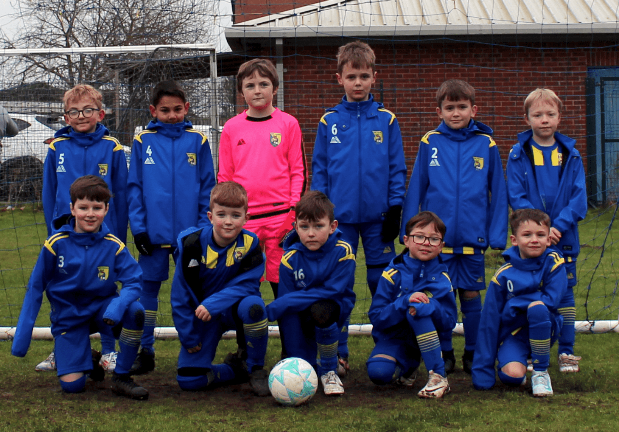 Under 9s Team Image shows the Carrr Vikings Under 9s football team looking to camera and smiling in their new football kits. The Kits are bluw and the goal keeper kit is pink.