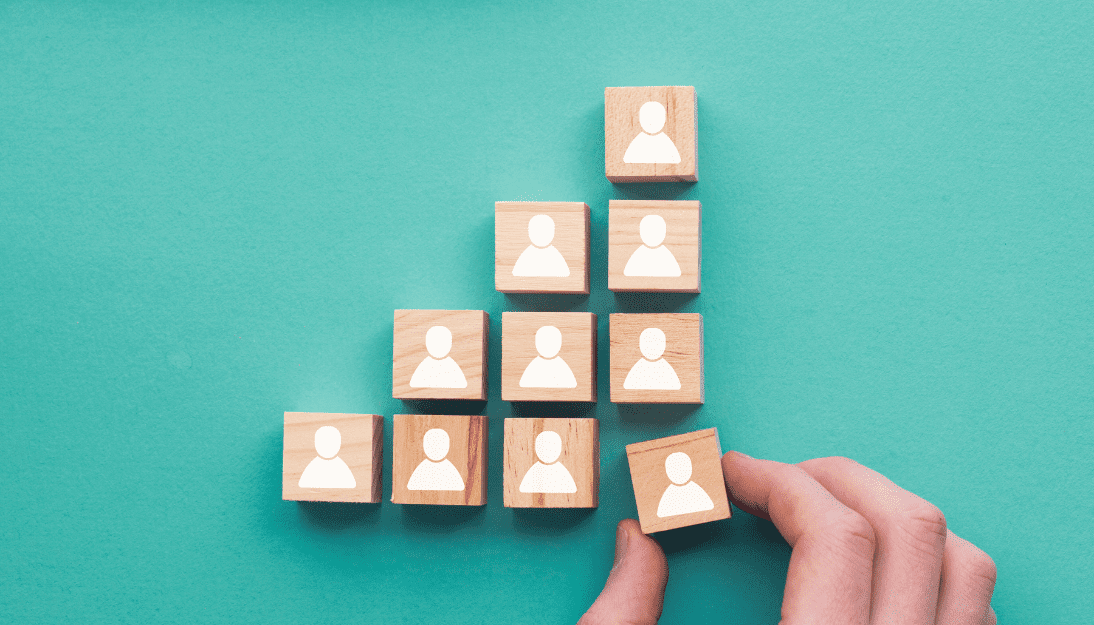 wooden blocks with a head and shoulders silhouette are shown stacked up with a hand moving another wooden block in to the pattern.