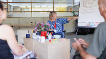 Impage of a white woman sat down next to a flip chart board