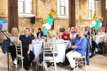 Image of volunteers sat down at tables enjoying a celebration event