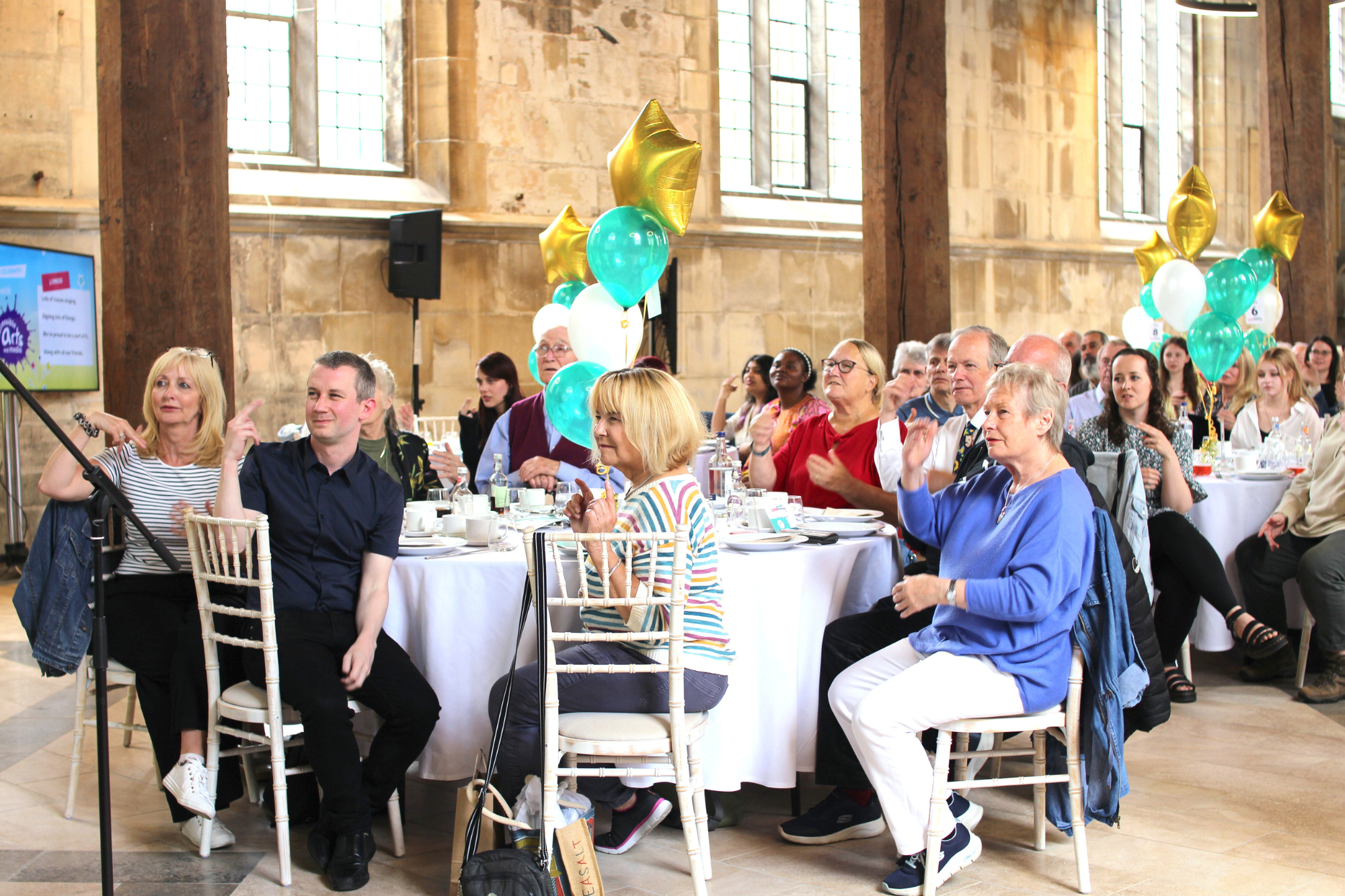 Image of volunteers sat down at tables enjoying a celebration event 