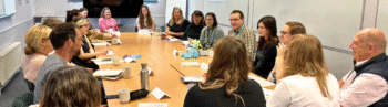 Image of group of people sat round a large meeting room table talking