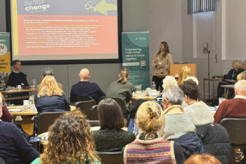 Image of a room full of people sat down watching a presentation