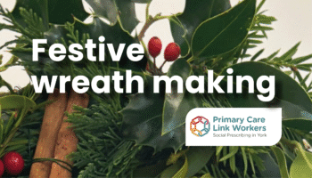Close-up of a festive wreath made from green foliage, red berries, and cinnamon sticks. Overlaid text reads: “Festive wreath making” with the Primary Care Link Workers logo below.
