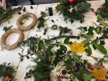 Image of a table with foliage and festive decorations during a wreath making class.