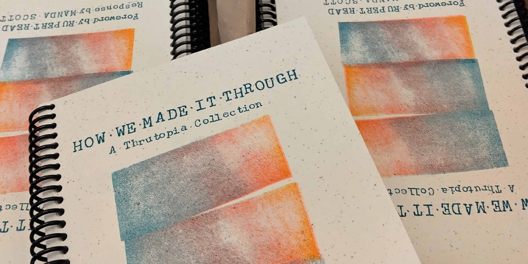 A box filled with spiral-bound copies of a booklet titled How We Made It Through: A Thrutopia Collection. The cover features abstract artwork in orange, blue and white tones, and includes a foreword by Rupert Read and a response by Manda Scott. The booklets are neatly stacked, some upright and some lying flat.