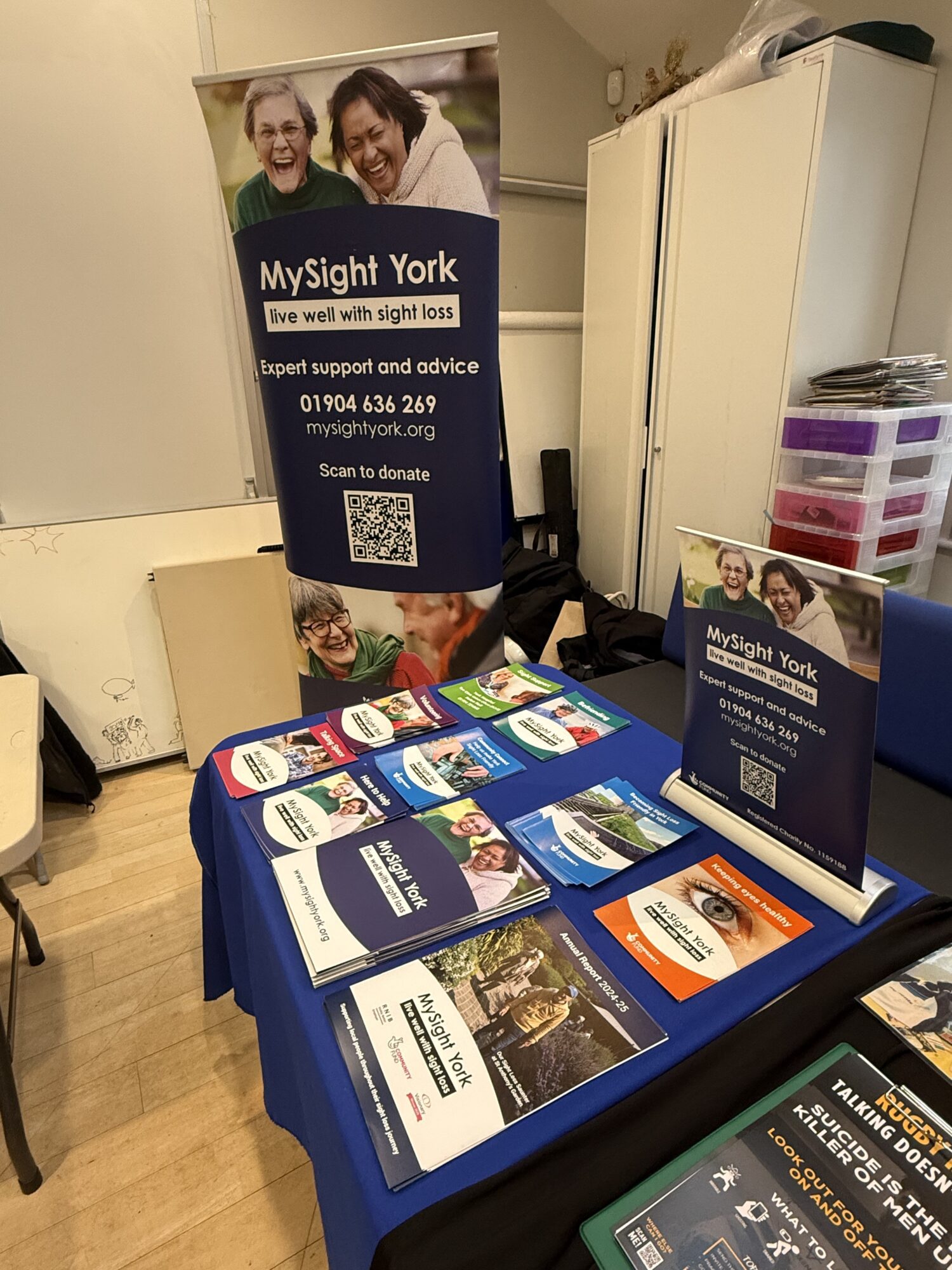 Information table and pull-up banners for MySight York, showing leaflets, booklets and contact details about support for people living with sight loss, displayed at an indoor event at the Clarence Street Hub in York.
