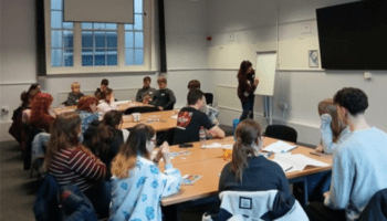 Image of young people sat round a table talking
